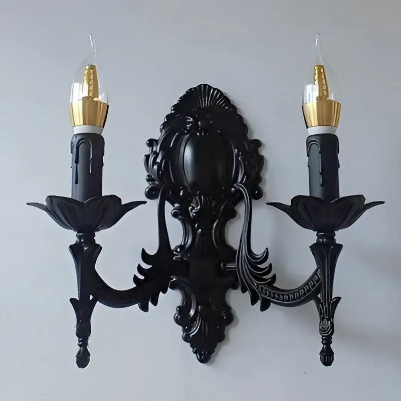 Black ornate wrought iron retro european wall sconce with two candle arms and gold finished bulb caps for bedroom use