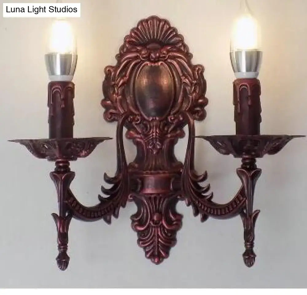 Antique gold bronze-colored ornate sconce with two candle-like bulbs for retro european wall light in bedroom