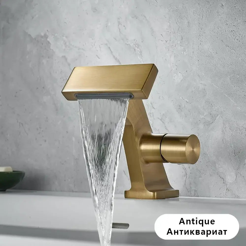 Antique gold waterfall single hole bathroom faucet with gold-toned rectangular spout and cylindrical handle