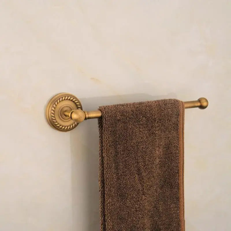 A plush brown towel hangs from an antique ornate decorbites brass round towel ring with decorative detailing