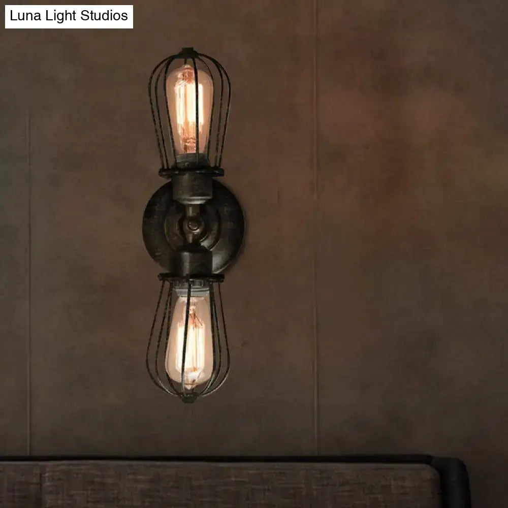 Antique style black bronze sconce light with two exposed filament bulbs in wire cages on a dark metal base for dining room