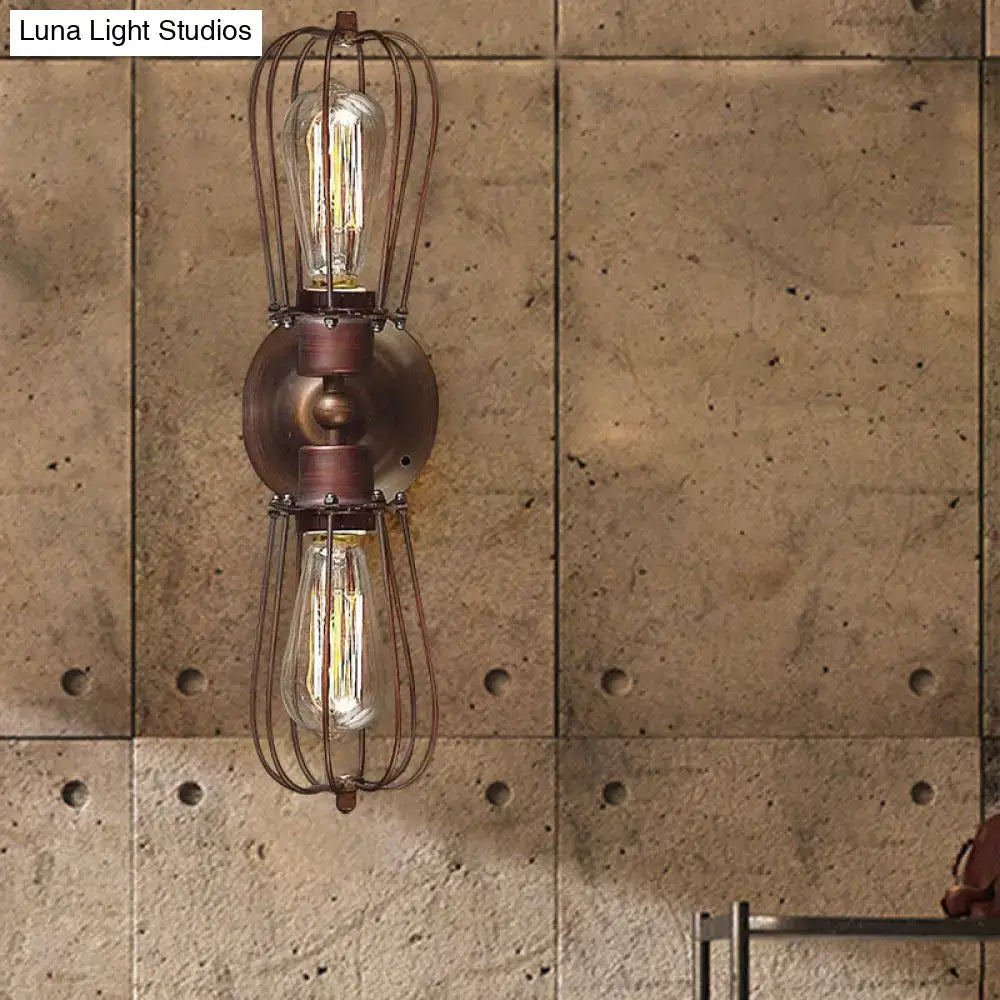 Antique style black bronze sconce light with two exposed filament bulbs in wire cages for dining room wall use