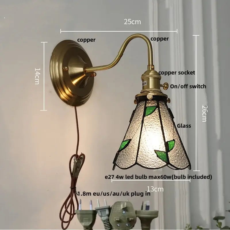 Antique brass wall light fixture with teal stained glass shade featuring green leaf motifs for bedroom use