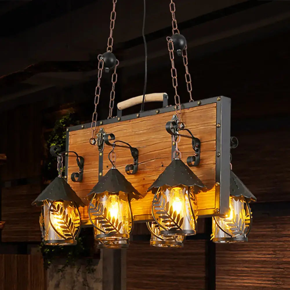 Rustic wooden panel with four hanging clear glass lanterns featuring leaf cutouts and black metal frames for dining room use