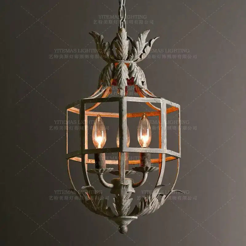 Antique wrought iron elegant candle chandelier with ornate leaf motifs and three glowing candle chandelier lights