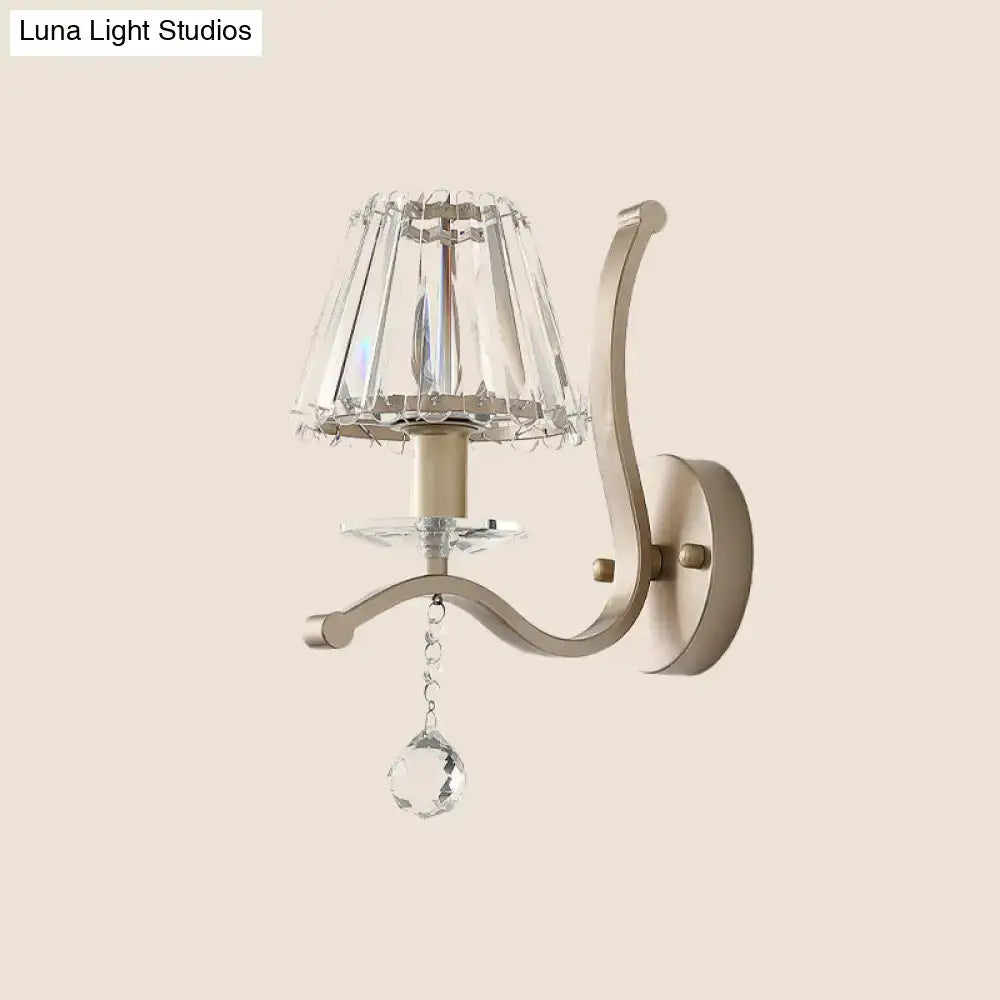 Elegant antiqued gold wall mount light fixture with faceted crystal shade and dangling teardrop crystal pendant