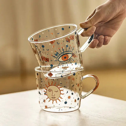 Clear 500ml glass mug with apricot and orange pattern featuring whimsical sun and eye celestial designs for breakfast use