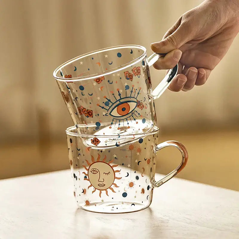 Clear 500ml glass mug with apricot and orange pattern featuring whimsical sun and eye celestial designs for breakfast use