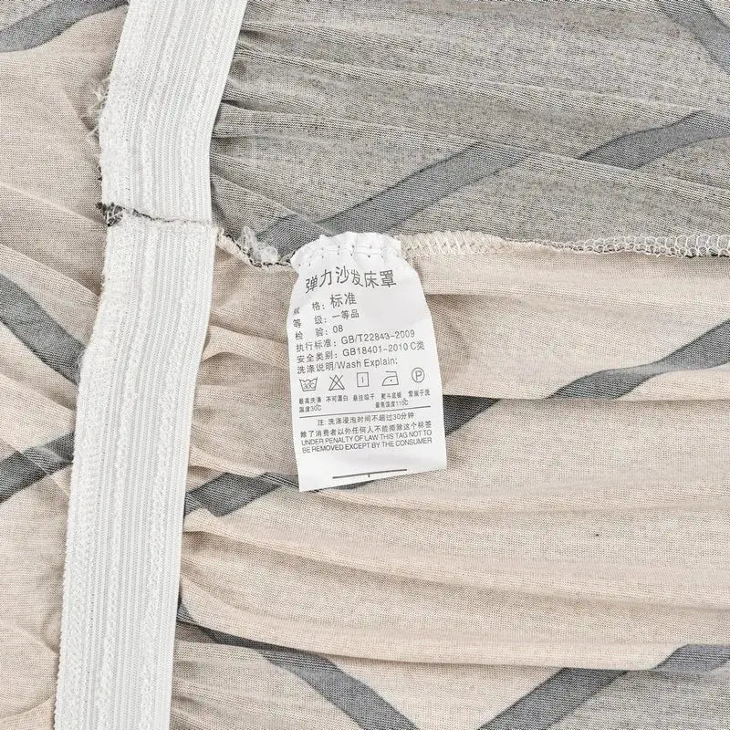 Beige and dark gray striped elastic sofa cover for armless futon bed with white care label attached