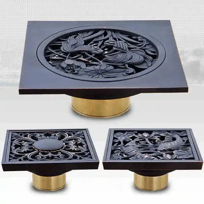 Black brass shower drain cover with intricate bird and flower carvings on a gold-toned metallic base decorbites black brass