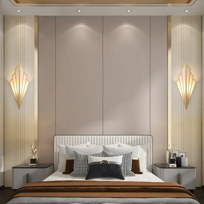 The bed with a white tufted headboard and black white brown pillows features an art deco black and cream led wall lamp