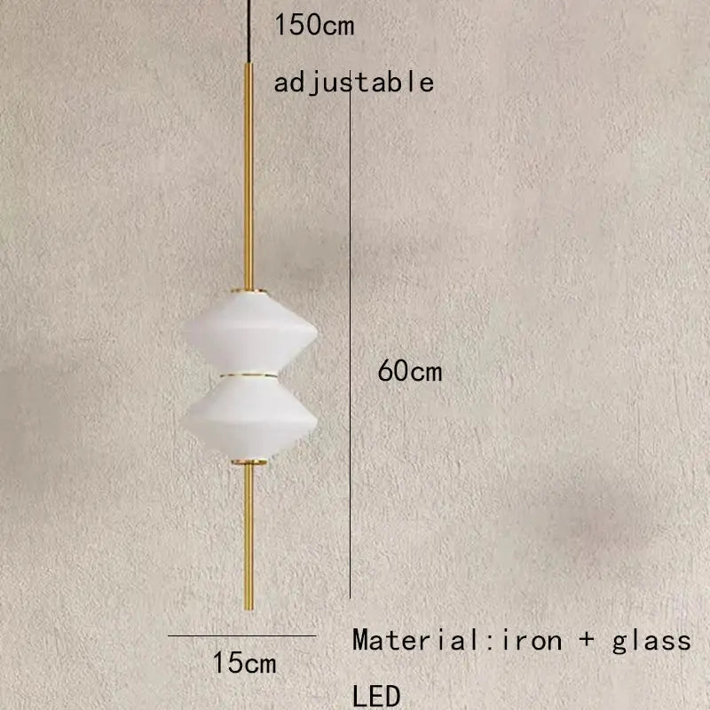 A modern art deco pendant light with two white faceted glass shades on a gold-toned iron rod for dining room