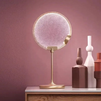 Circular vanity mirror with textured frosted glass and gold-toned frame paired with decorbites clear pink glass pendant light