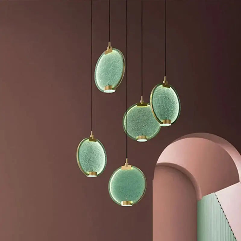 Five oval pendant lights with textured green glass and gold fixtures complement decorbites clear pink glass decor