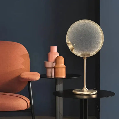 A sleek circular table lamp with clear pink glass dome and gold-toned metal base perfect as decorbites pendant light