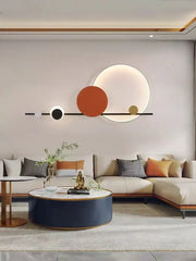 Modern geometric art deco led wall sconce with black orange and gold circular elements on light gray wall