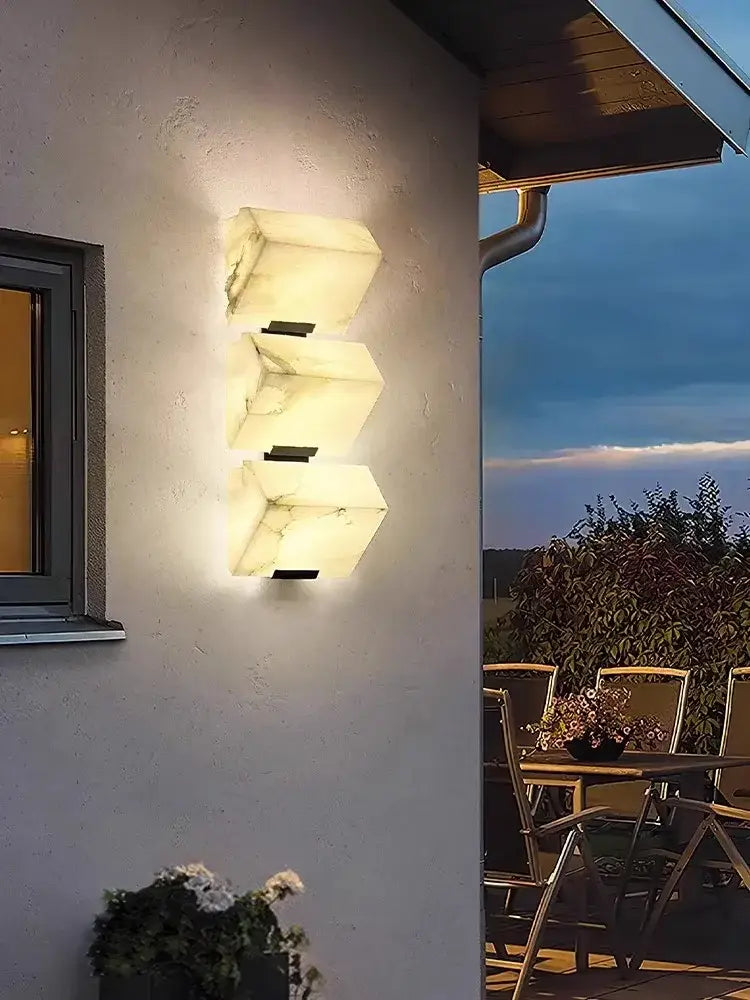 Modern three-light wall sconce with warm glowing white marble panels for decorbites art deco marble living room decor