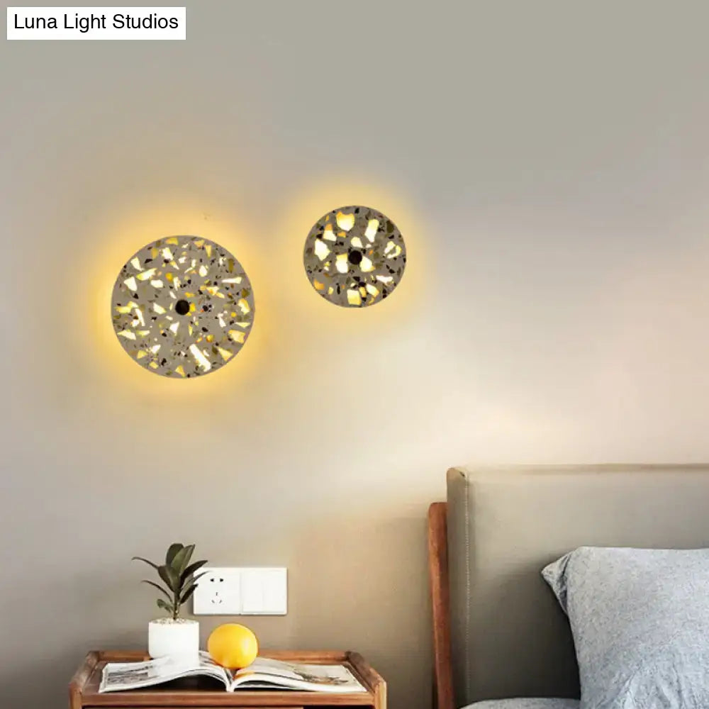 Circular mosaic terrazzo led wall sconce with textured gray and white finish emitting warm light for living room use