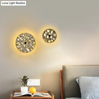 Circular mosaic terrazzo led wall sconce with textured gray and white finish emitting warm light for living room use