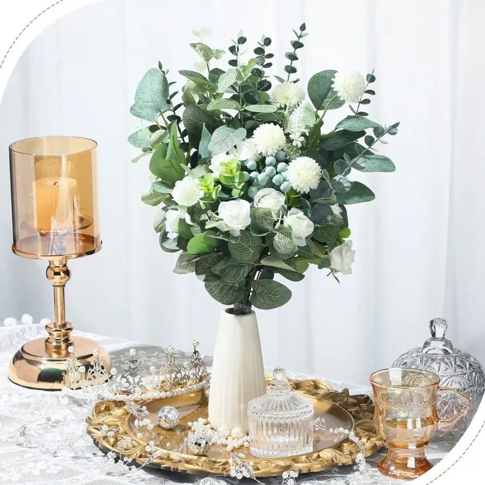 A lush artificial flower plants eucalyptus stems arrangement with white flowers and blue accents in a tall white vase