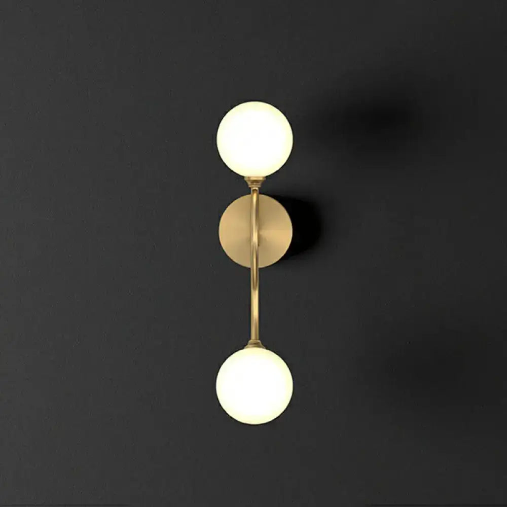 Modern brass artistic wall lighting fixture with two milky glass spherical shades for bedroom use