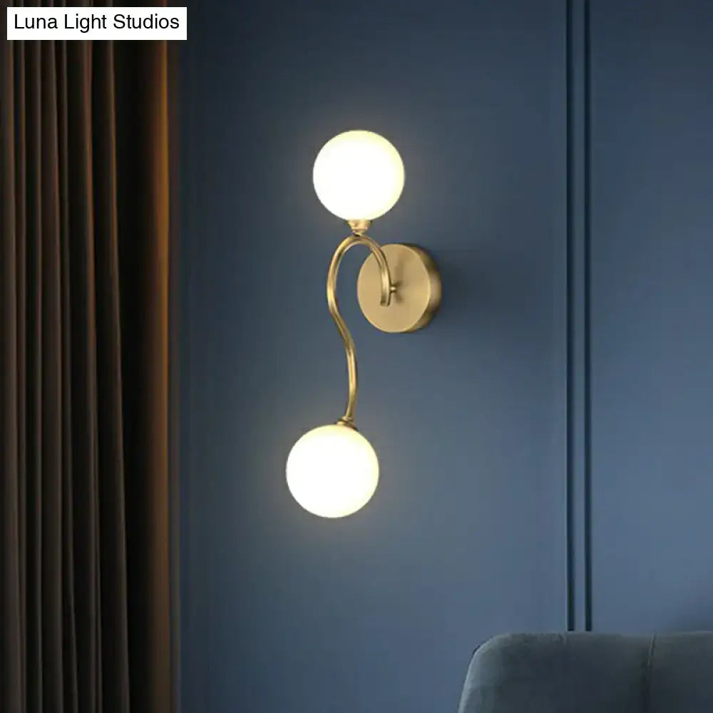 Artistic gold spherical wall lighting fixture with milky glass globes and elegant curved arm for bedroom use