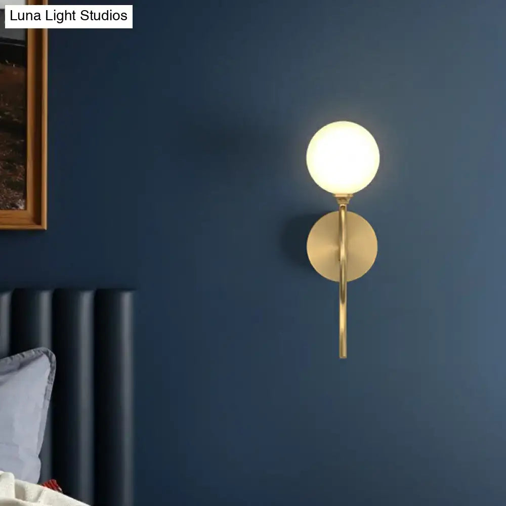 Artistic gold spherical wall lighting fixture with frosted glass globe and minimalist circular base for bedroom use