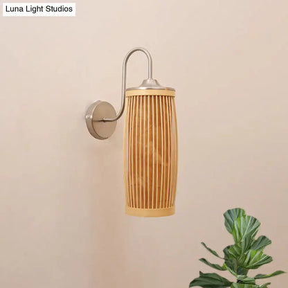 A sleek wall lamp with a cylindrical bamboo shade and brushed metal hardware featuring a gooseneck arm