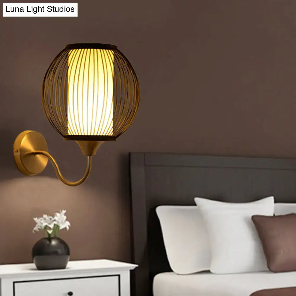 Golden wireframe wall lamp with a warm glowing cylindrical shade and black bamboo gooseneck arm wall light for bedroom