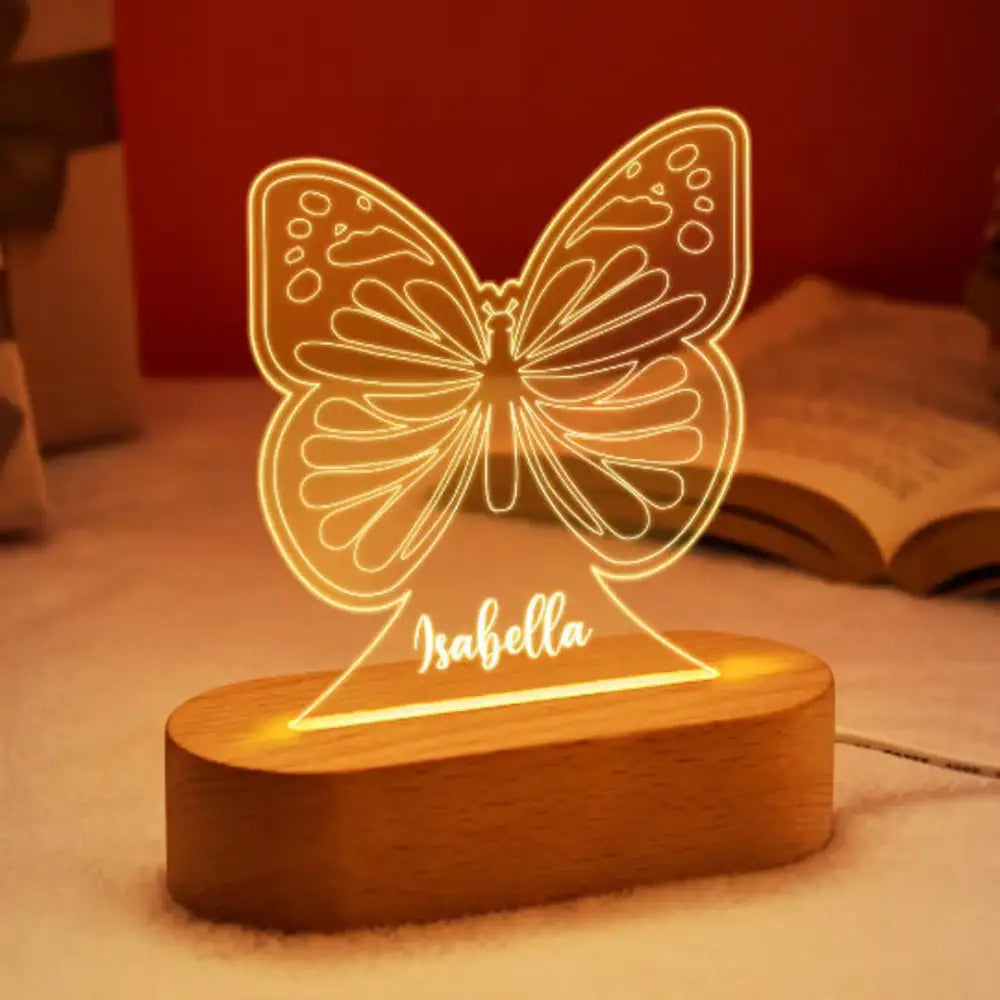 A warm glowing butterfly shaped led night light with a personalized children name engraved on its wooden base