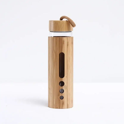 A sleek glass water bottle with a natural bamboo sleeve and lid featuring vertical slits and a rope handle