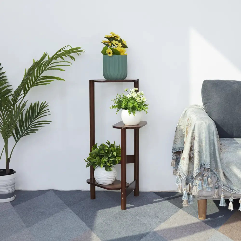 Dark brown wooden bamboo tall corner plant stand with three tiers and angled legs holding various potted plants