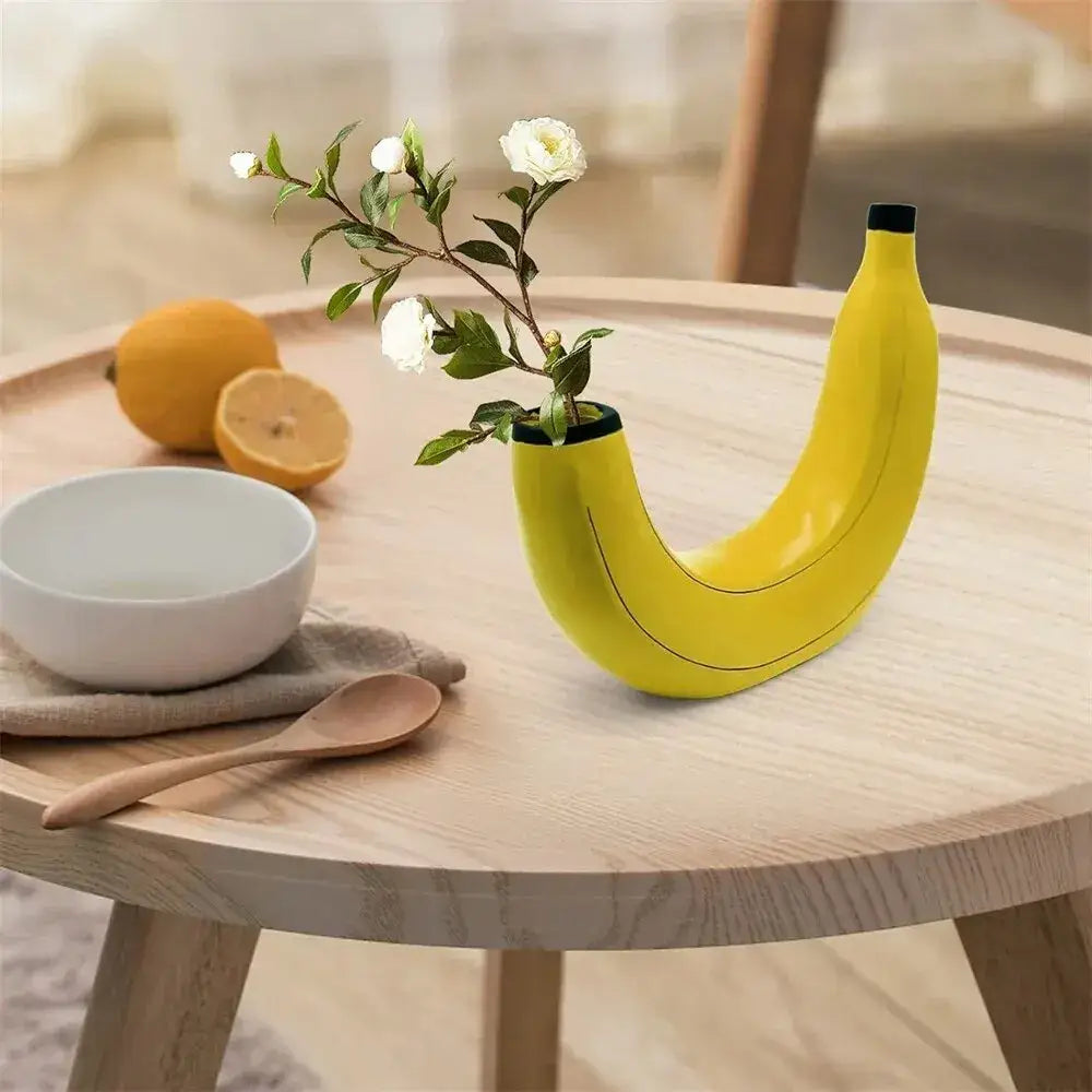 Bright yellow banana shape resin flower vase with black rim holding delicate white flowers for decoration