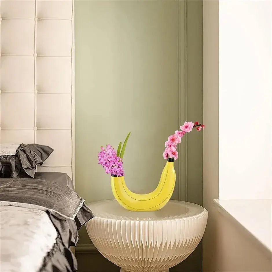 Yellow banana shape resin flower vase holding pink and purple flowers for decorative use