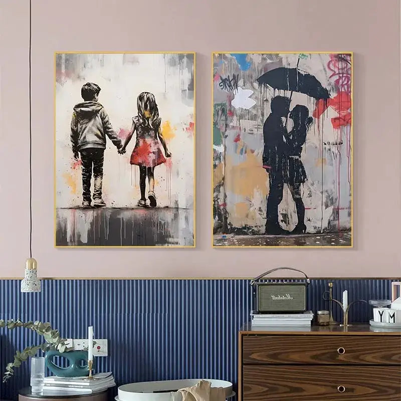 Two framed banksy canvas prints featuring boy girl balloon and couple under umbrella with black silhouettes on graffiti backgrounds