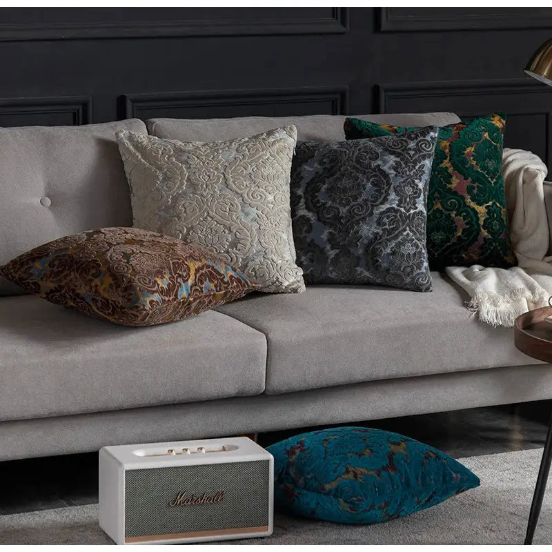 White Marshall speaker with textured grille and gold-tone logo alongside beige decorbites damask cut velvet cushion covers