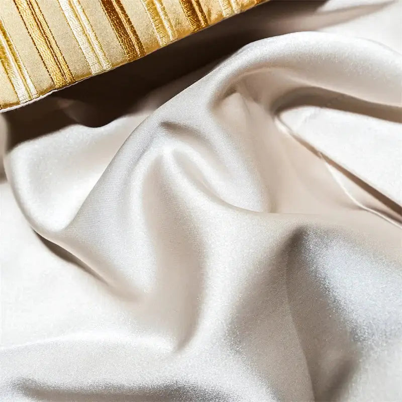 Cream-colored satin fabric with smooth glossy finish and folds in baroque blue and gold embroidered cotton bedding set