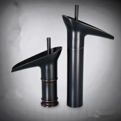 Two matte black deck mounted bathroom faucets with copper accents featuring antique brass waterfall spouts and metered valve control