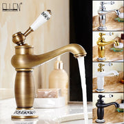 Antique brass bathroom faucet with bronze finish white ceramic handle and black ornate detailing on decorative base