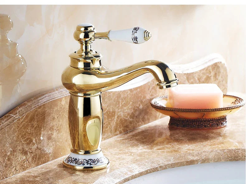 Bathroom faucet with bronze finish gold detailing white ceramic handle and black floral decorative base