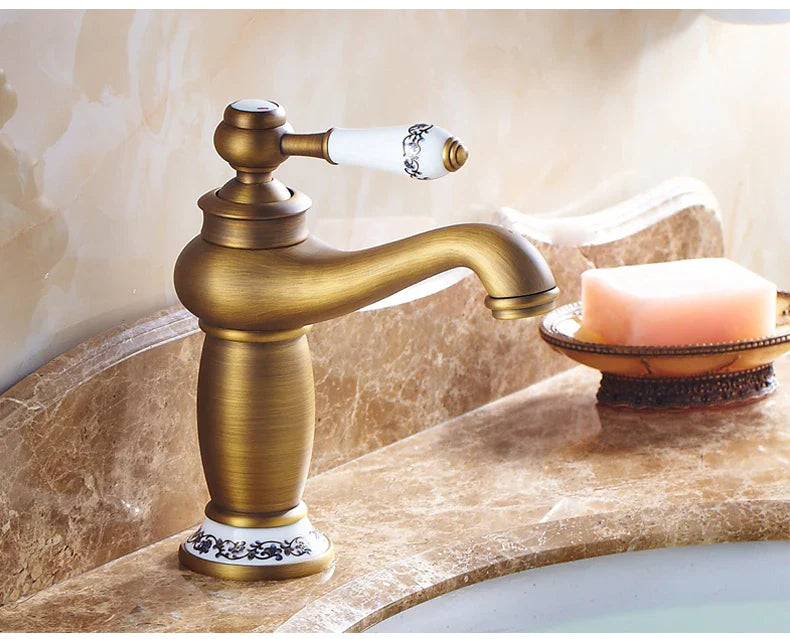 Antique brass bathroom faucet with bronze finish white ceramic handle and ornate black floral detailing