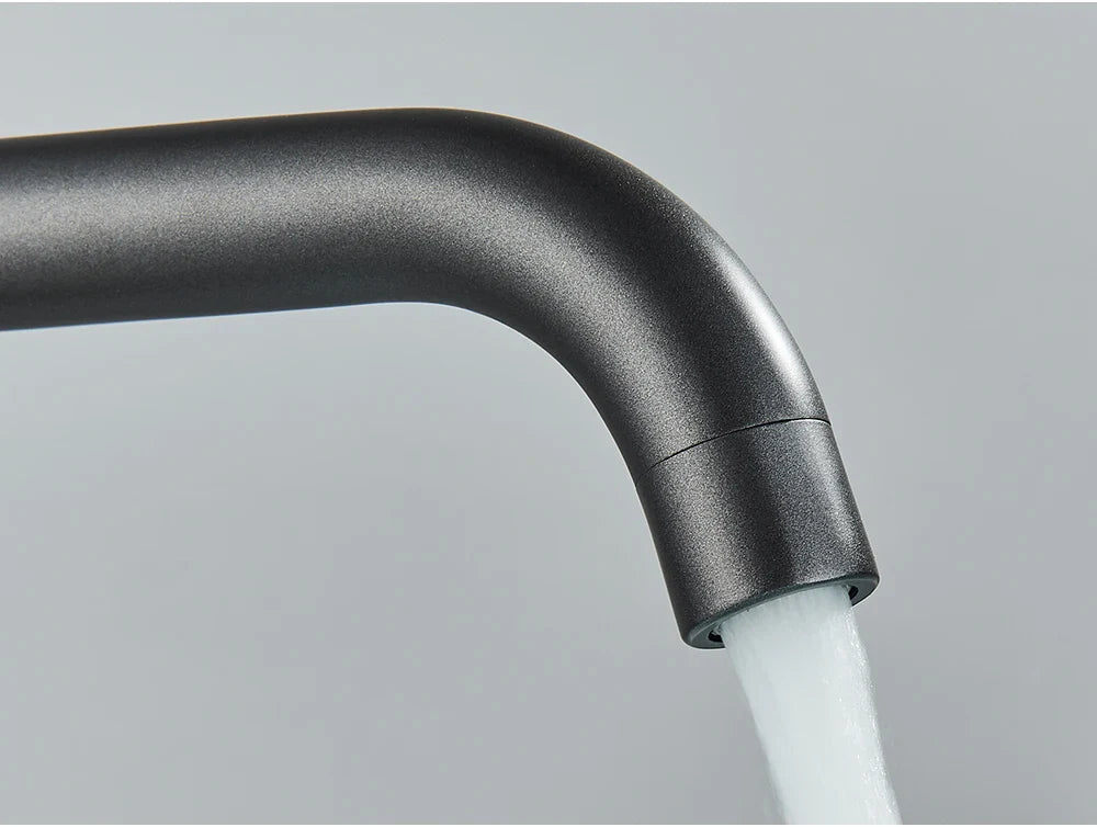 Matte black bathroom faucet with sleek curved design and water flowing from spout for brushed gold mixer tap use