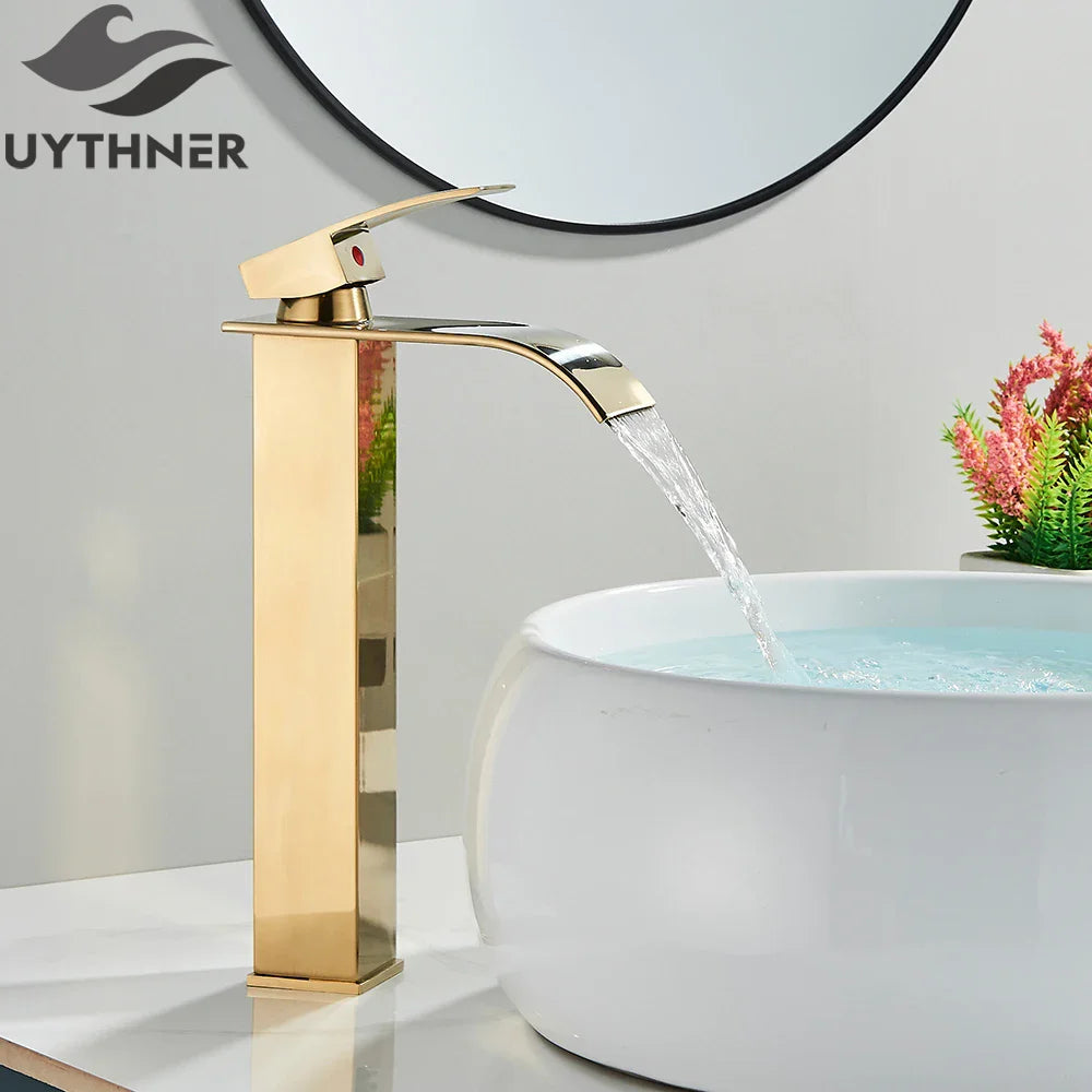 Gold finished bathroom sink faucet with stainless steel waterfall design and single red accent button deck mount