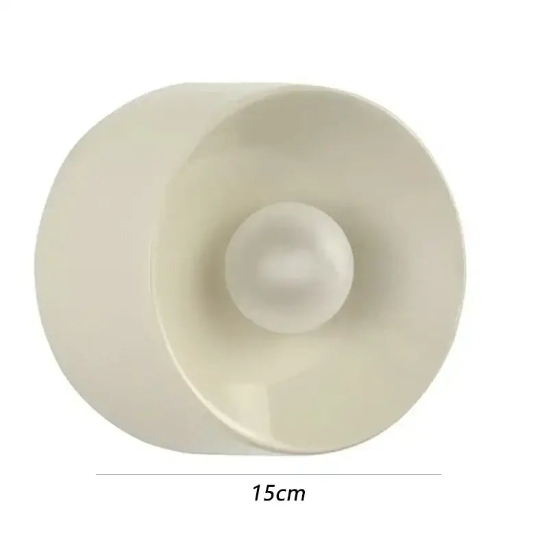 Cream-colored translucent plastic candle holder with spherical base and flared rim complementing bauhaus metal wall lamp