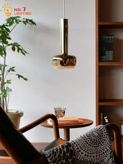 A sleek modern bauhaus copper chrome pendant light with polished brass finish and cylindrical design for kitchen island