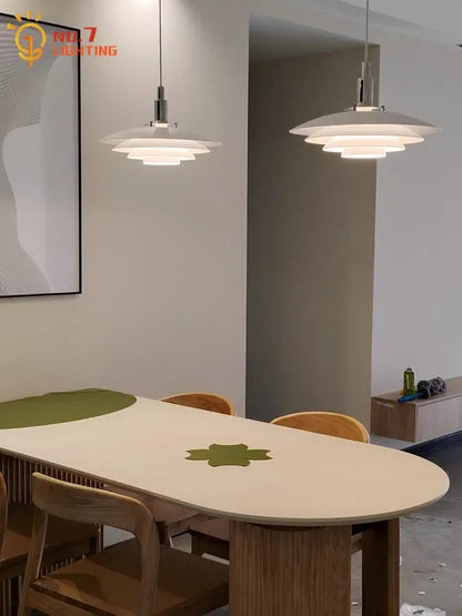 Modern white bauhaus flying saucer pendant light with layered disc-shaped shades and sleek metallic fixtures above dining table
