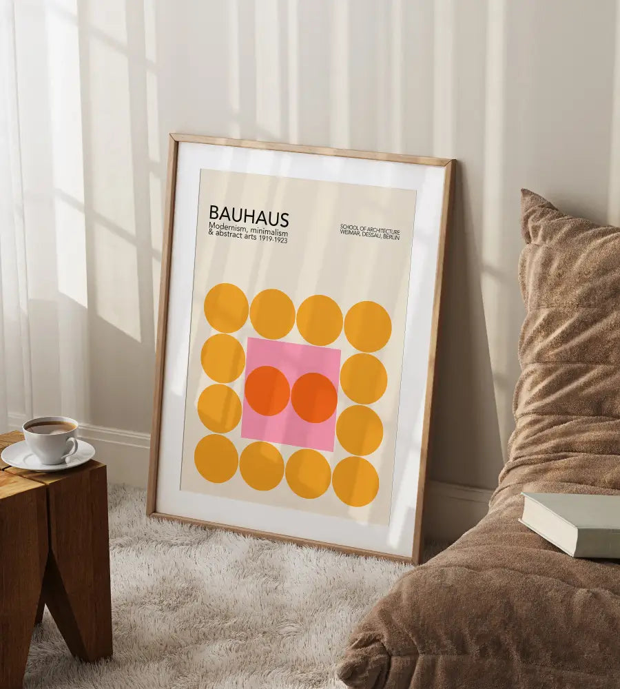 A framed DecorBites™ bauhaus geometric canvas print with yellow and pink circles in a light wood frame
