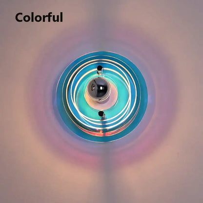 A vibrant bauhaus led wall light featuring a red circular sconce with iridescent blue teal glass rings and a black center sphere