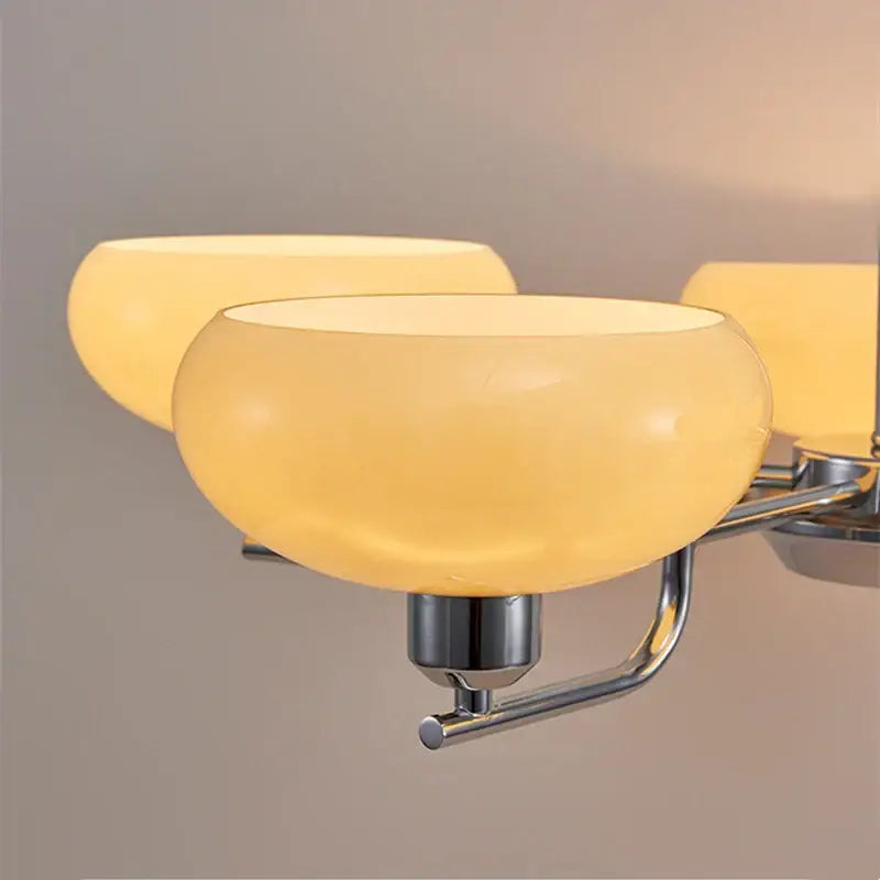 Warm amber glass bowl-shaped light fixtures with polished chrome arms in a bauhaus medieval chandelier for living rooms