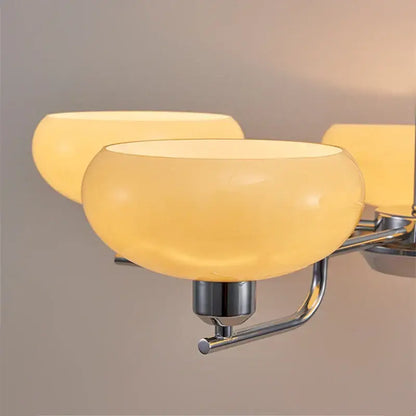 Warm amber glass bowl-shaped light fixtures with polished chrome arms in a bauhaus medieval chandelier for living rooms